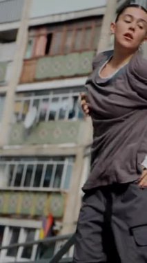 Dikey. Şehir koreografisi beton basamaklarda, zarafet ve güçle hareket eden bir kadın olarak gözler önüne seriliyor. Hip-hop hareketleri, şehir binalarına karşı bir enerji patlaması. Sokak stili dansla buluşur. Somut adımlar, hip-hop sanatının bir sahnesi., 