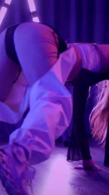 Dikey. Baştan çıkarıcı dans eden seksi kadın. Titreyen bir dansçı, canlı mor ve mavi ışıkla yıkanmış, canlı neon bir üçgenin altında sahnenin enerjisini somutlaştırıyor. Bir sanatçının kadın vücudu.