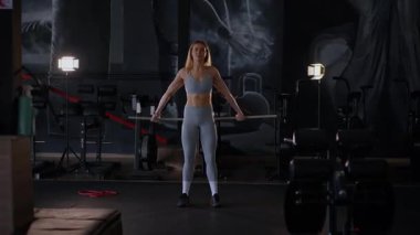 Spor salonunda egzersiz yapan kaslı bir kadın. Atletizm antrenmanı. Güzel vücudunu ve vücut şeklini gösteren güçlü atletik kadın..