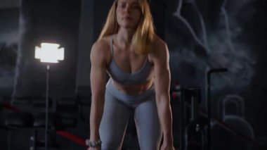 Spor salonunda egzersiz yapan kaslı bir kadın. Atletizm antrenmanı. Güzel vücudunu ve vücut şeklini gösteren güçlü atletik kadın..