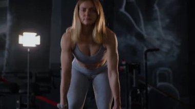Spor salonunda egzersiz yapan kaslı bir kadın. Atletizm antrenmanı. Güzel vücudunu ve vücut şeklini gösteren güçlü atletik kadın..