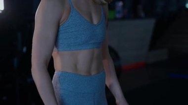 Spor salonunda egzersiz yapan kaslı bir kadın. Atletizm antrenmanı. Güzel vücudunu ve vücut şeklini gösteren güçlü atletik kadın..