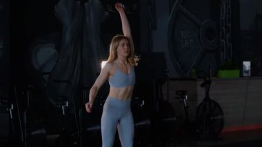 Spor salonunda egzersiz yapan kaslı bir kadın. Atletizm antrenmanı. Güzel vücudunu ve vücut şeklini gösteren güçlü atletik kadın..