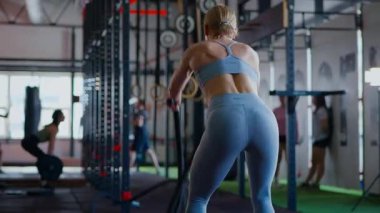 Spor salonunda egzersiz yapan kaslı bir kadın. Atletizm antrenmanı. Güzel vücudunu ve vücut şeklini gösteren güçlü atletik kadın..