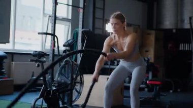 Spor salonunda egzersiz yapan kaslı bir kadın. Atletizm antrenmanı. Güzel vücudunu ve vücut şeklini gösteren güçlü atletik kadın..