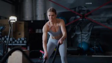 Spor salonunda egzersiz yapan kaslı bir kadın. Atletizm antrenmanı. Güzel vücudunu ve vücut şeklini gösteren güçlü atletik kadın..