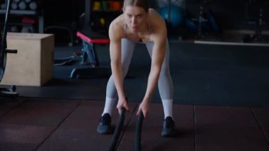 Spor salonunda egzersiz yapan kaslı bir kadın. Atletizm antrenmanı. Güzel vücudunu ve vücut şeklini gösteren güçlü atletik kadın..