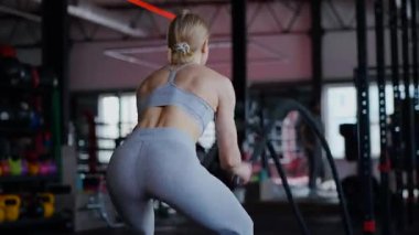 Spor salonunda egzersiz yapan kaslı bir kadın. Atletizm antrenmanı. Güzel vücudunu ve vücut şeklini gösteren güçlü atletik kadın..