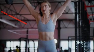 Spor salonunda egzersiz yapan kaslı bir kadın. Atletizm antrenmanı. Güzel vücudunu ve vücut şeklini gösteren güçlü atletik kadın..