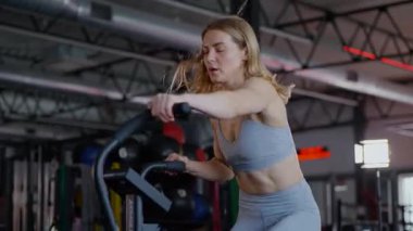 Spor salonunda egzersiz yapan kaslı bir kadın. Atletizm antrenmanı. Güzel vücudunu ve vücut şeklini gösteren güçlü atletik kadın..