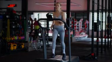 Spor salonunda egzersiz yapan kaslı bir kadın. Atletizm antrenmanı. Güzel vücudunu ve vücut şeklini gösteren güçlü atletik kadın..