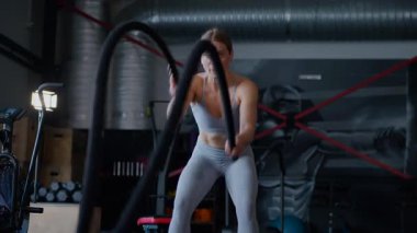 Spor salonunda egzersiz yapan kaslı bir kadın. Atletizm antrenmanı. Güzel vücudunu ve vücut şeklini gösteren güçlü atletik kadın..