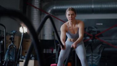 Spor salonunda egzersiz yapan kaslı bir kadın. Atletizm antrenmanı. Güzel vücudunu ve vücut şeklini gösteren güçlü atletik kadın..