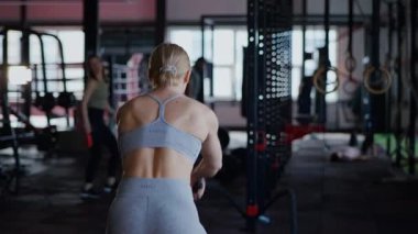 Spor salonunda egzersiz yapan kaslı bir kadın. Atletizm antrenmanı. Güzel vücudunu ve vücut şeklini gösteren güçlü atletik kadın..