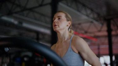Spor salonunda egzersiz yapan kaslı bir kadın. Atletizm antrenmanı. Güzel vücudunu ve vücut şeklini gösteren güçlü atletik kadın..