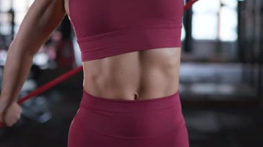 Kas dalgalanmaları koyu kahverengi spor sutyen ve şortun altında. Odaklanmış kararlılık. Spor salonunda, yoğun bir şekilde antrenmanına odaklanan bir kadın..