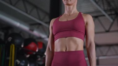 Kas dalgalanmaları koyu kahverengi spor sutyen ve şortun altında. Odaklanmış kararlılık. Spor salonunda, yoğun bir şekilde antrenmanına odaklanan bir kadın..