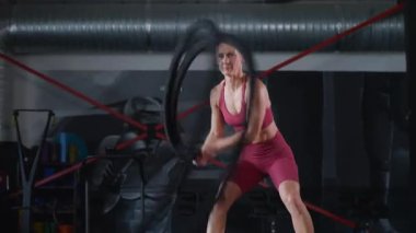 Spor salonunda ip eğitimi alan bir kadın. Kadınlar için ağır ip kaldırma egzersizleri.