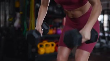 Dambılları başının üstüne sertçe kaldıran bir kadının karın kasları. Bir sporcunun kardiyo eğitimi ve sporu.