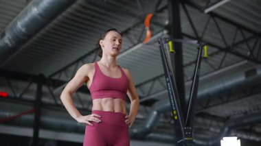 Kararlı bir sporcu, odaklanmış bakışlar, spor salonunda sınırları zorlamak. Rosy fitness kıyafeti, heykeltraş fiziği, yoğun bir konsantrasyon anı..