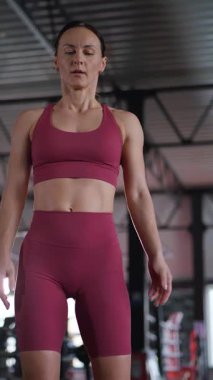 Dikey olarak. Kararlı bir sporcu, odaklanmış bakışlar, spor salonunda sınırları zorlamak. Rosy fitness kıyafeti, heykeltraş fiziği, yoğun bir konsantrasyon anı..