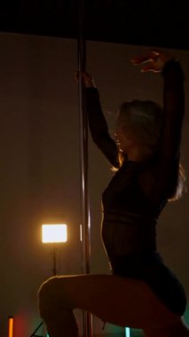 Dikey olarak. Loş stüdyoda, direğin üzerinde büyüleyici bir dans başlıyor. Kadın dansçının silueti direğe karşı. Havada asılı kalmış, zarif bir şekilde direğe tutunan bir dansçı. Egzotik direk