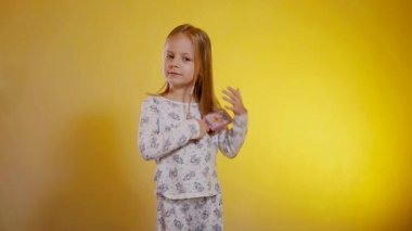 Desenli pijamalı genç bir kız saçını tarıyor. Çocuk sabah yattıktan sonra saçını yapıyor..