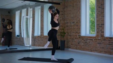 Bir kadın esneme ve pilates yapıyor. Parlak bir stüdyoda esneyen ve dengeyi bulan zarif bir kadın pozu. Gökyüzüne uzanan bir kadın, içindeki gücü yoga akışında bulur. Siyah giysi, odaklanmış ifade