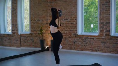 Bir kadın esneme ve pilates yapıyor. Parlak bir stüdyoda esneyen ve dengeyi bulan zarif bir kadın pozu. Gökyüzüne uzanan bir kadın, içindeki gücü yoga akışında bulur. Siyah giysi, odaklanmış ifade