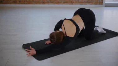 Bir kadın esneme ve pilates yapıyor. Parlak bir stüdyoda esneyen ve dengeyi bulan zarif bir kadın pozu. Gökyüzüne uzanan bir kadın, içindeki gücü yoga akışında bulur. Siyah giysi, odaklanmış ifade