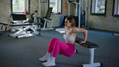 Pembe taytlı bir kadının aktif fitness eğitimi ve güzel bir vücut şekli olan beyaz bir bluz. Spor salonundaki genç bir kadının spor eğitimi.