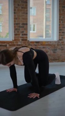 Dikey. Bir kadın stüdyoda esneme hareketleri yapıyor ve pilates yapıyor. Parlak bir stüdyoda esneyen ve dengeyi bulan zarif bir kadın pozu. Gökyüzüne uzanan bir kadın, içindeki gücü yoga akışında bulur. Siyah elbise.,