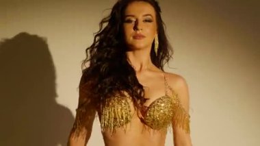 Güzel genç bir kadın göbek dansı yapıyor. Altın elbiseli bir kadın dansçının silueti. Doğulu göbek dansı.