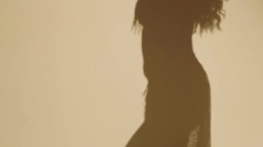 Güzel genç bir kadın göbek dansı yapıyor. Altın elbiseli bir kadın dansçının silueti. Doğulu göbek dansı.