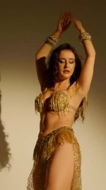 Büyüleyici bir dansçı, altın içinde parıldayan, hareketleri büyüleyici bir manzara. Altın ışık bir dansçının zarif şeklini aydınlatır, göbek dansının sanatını gözler önüne serer..