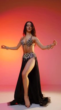 Dikey. Siyah sutyen ve etekle göbek dansı yapan güzel bir genç kadın. Güzel vücutlu narin bir kız doğu dansları yapar. Doğulu göbek dansı.