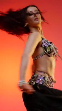 Dikey. Siyah sutyen ve etekle göbek dansı yapan güzel bir genç kadın. Güzel vücutlu narin bir kız doğu dansları yapar. Doğulu göbek dansı.