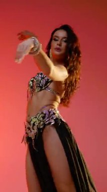 Dikey. Siyah sutyen ve etekle göbek dansı yapan güzel bir genç kadın. Güzel vücutlu narin bir kız doğu dansları yapar. Doğulu göbek dansı.