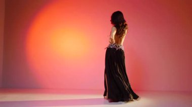 Siyah sutyen ve etekle göbek dansı yapan güzel bir genç kadın. Güzel vücutlu narin bir kız doğu dansları yapar. Doğulu göbek dansı.