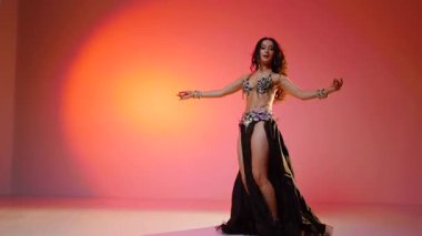 Siyah sutyen ve etekle göbek dansı yapan güzel bir genç kadın. Güzel vücutlu narin bir kız doğu dansları yapar. Doğulu göbek dansı.