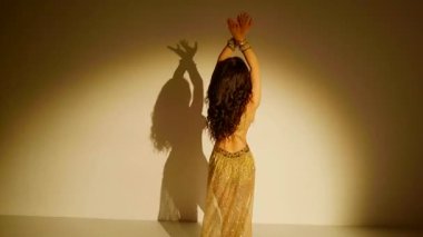 Sarı baştan çıkarıcı bir kıyafetle göbek dansı yapan güzel bir kadın. Ağır çekim. Güzel bir vücut dansı yapan oryantal dansçı kız. Doğulu göbek dansı.