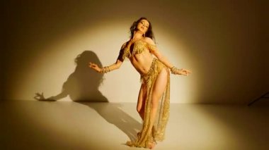Sarı baştan çıkarıcı bir kıyafetle göbek dansı yapan güzel bir kadın. Ağır çekim. Güzel bir vücut dansı yapan oryantal dansçı kız. Doğulu göbek dansı.