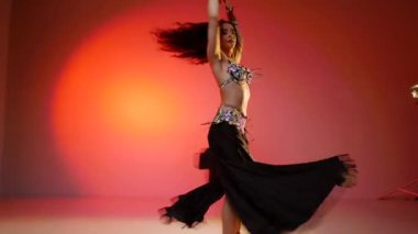 Siyah sutyen ve etekle göbek dansı yapan güzel bir genç kadın. Güzel vücutlu narin bir kız doğu dansları yapar. Doğulu göbek dansı.