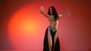 Siyah sutyen ve etekle göbek dansı yapan güzel bir genç kadın. Güzel vücutlu narin bir kız doğu dansları yapar. Doğulu göbek dansı.