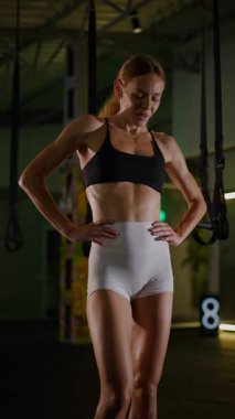 Dikey. Güzel vücutlu bir kadın spor salonundaki ağır egzersizlerden dinleniyor. Güzel genç sporcu egzersizler arasında inanılmaz bir vücut gösterisi sergiliyor..