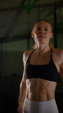 Dikey. Güzel vücutlu bir kadın spor salonundaki ağır egzersizlerden dinleniyor. Güzel genç sporcu egzersizler arasında inanılmaz bir vücut gösterisi sergiliyor..