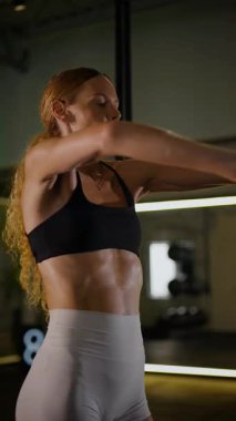 Dikey. Bir kadının güçlü fiziği esneme hareketleri yapıyor. Fitness iş başında. Antrenman devam ediyor. Bir kadının kendini spora adaması, kararlı duruşunda bellidir..