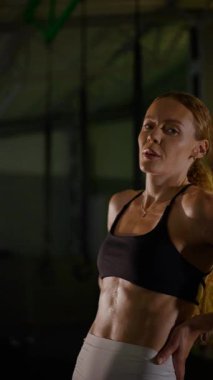 Dikey. Güzel vücutlu bir kadın spor salonundaki ağır egzersizlerden dinleniyor. Güzel genç sporcu egzersizler arasında inanılmaz bir vücut gösterisi sergiliyor..