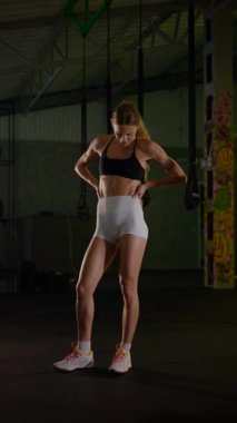 Dikey. Güzel vücutlu bir kadın spor salonundaki ağır egzersizlerden dinleniyor. Güzel genç sporcu egzersizler arasında inanılmaz bir vücut gösterisi sergiliyor..