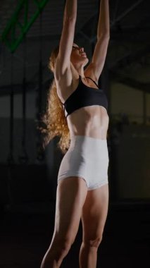 Dikey. Bir kadının güçlü fiziği esneme hareketleri yapıyor. Fitness iş başında. Antrenman devam ediyor. Bir kadının kendini spora adaması, kararlı duruşunda bellidir..